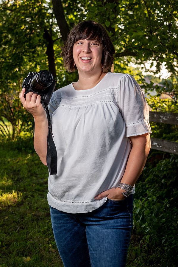 A woman is holding a camera in her hand and smiling.