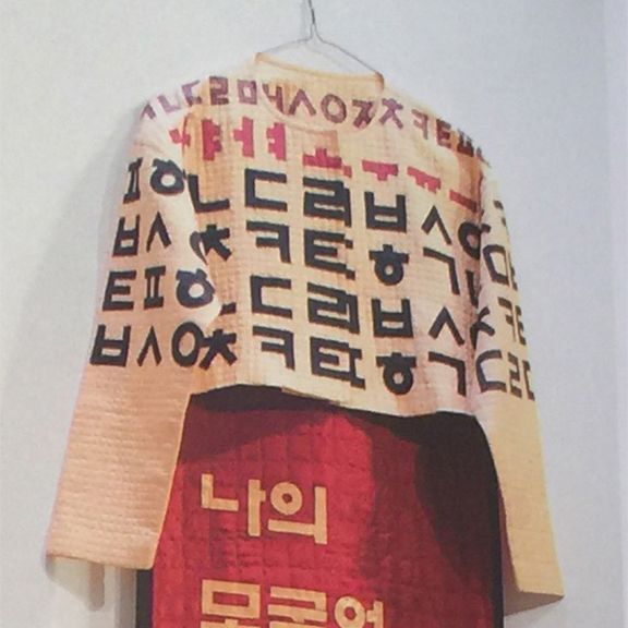 A shirt with korean writing on it hangs on a hanger