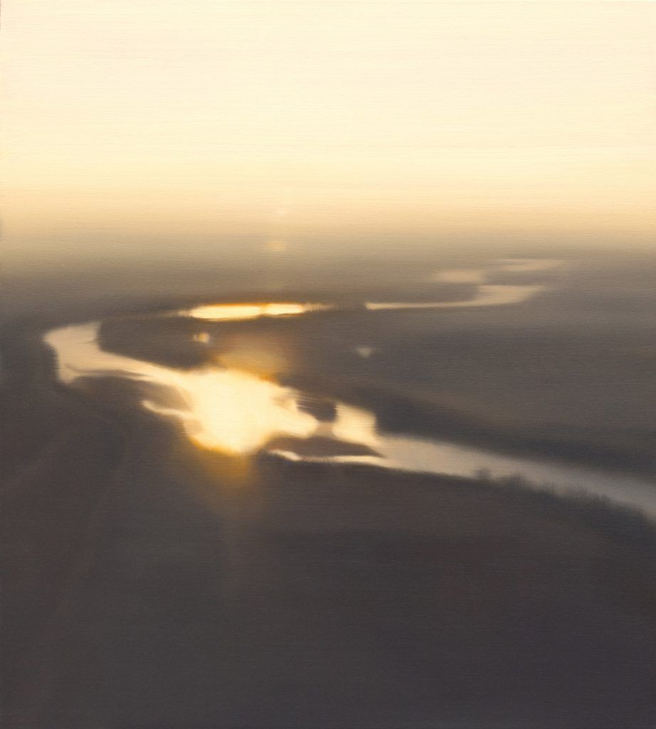An aerial view of a river at sunset with the sun shining through the water.