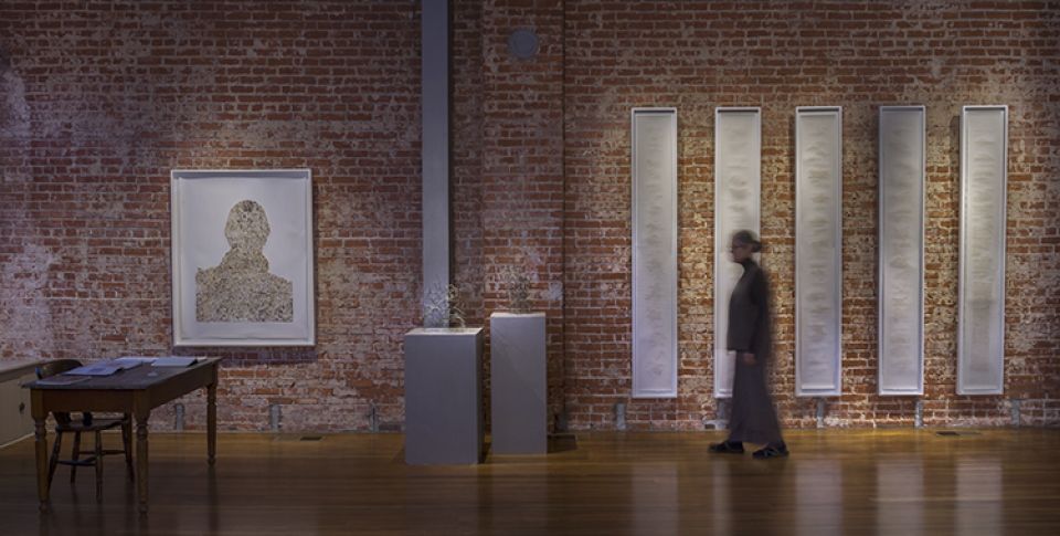 A man is walking through a museum with a brick wall.