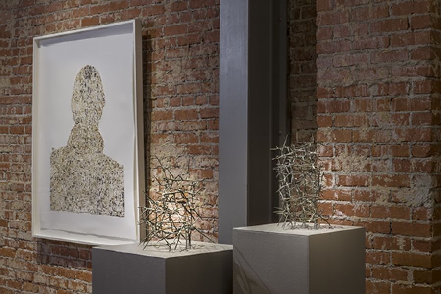 There are two sculptures on display in front of a brick wall.