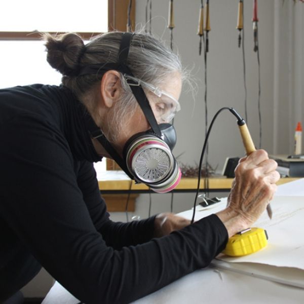 A woman wearing a gas mask is working on a piece of paper