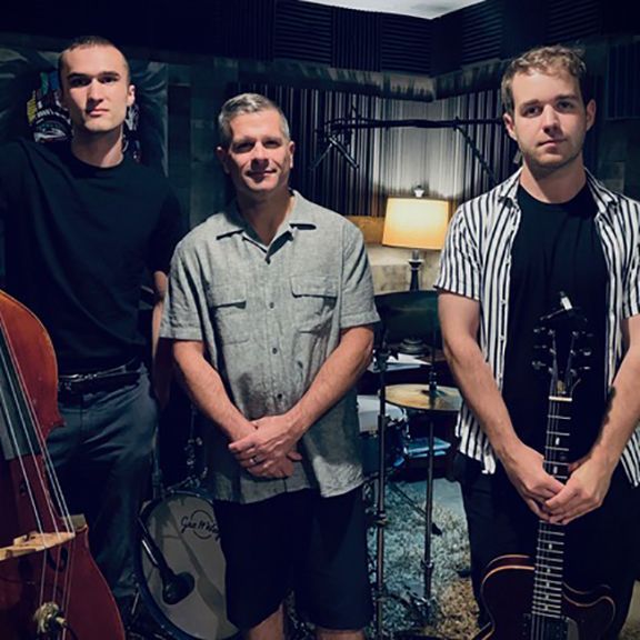 Three men standing next to each other in a room with instruments