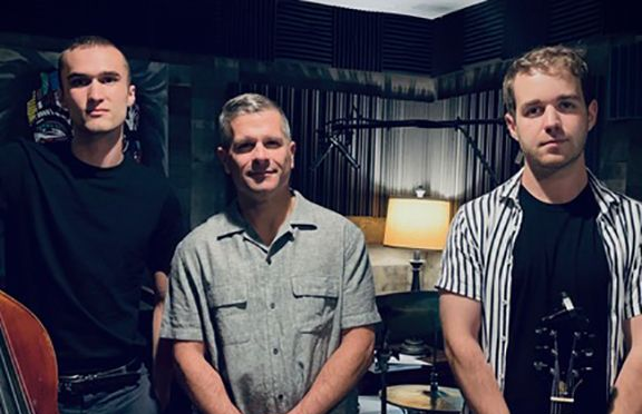 Three men standing next to each other in a room with instruments