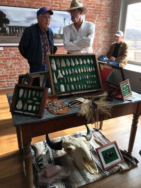 Three men are standing around a table with a buffalo skull on it
