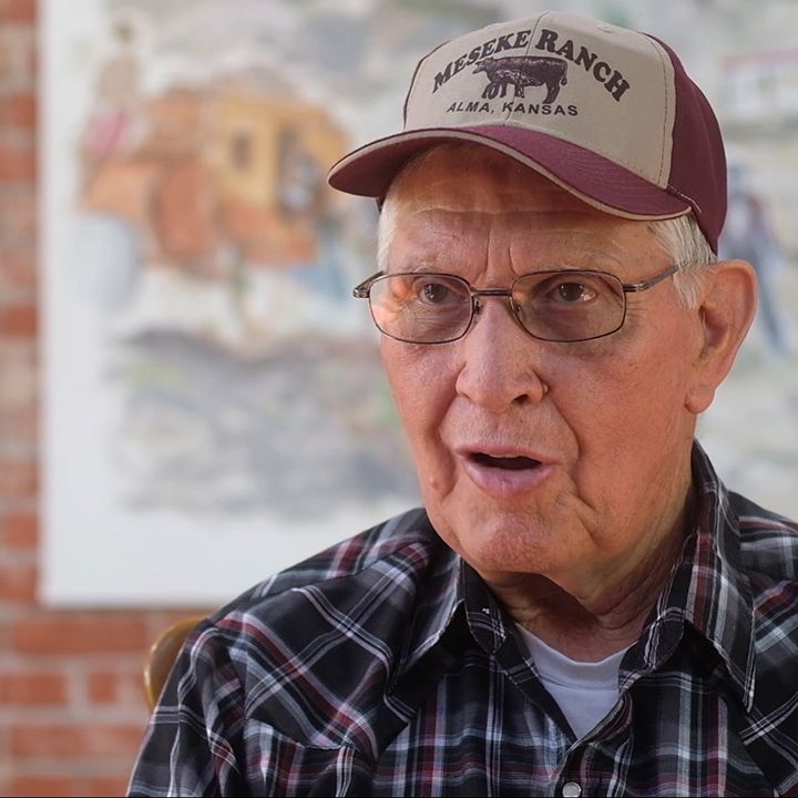 Elderly man wearing a hat that reads