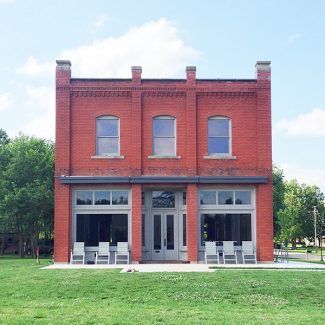 A large red brick building with a lot of windows and chairs in front of it.