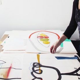 A woman is standing at a table with a painting on it.