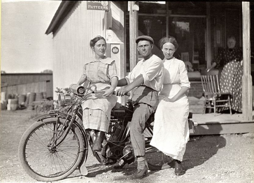 A man sits on a motorcycle next to two women