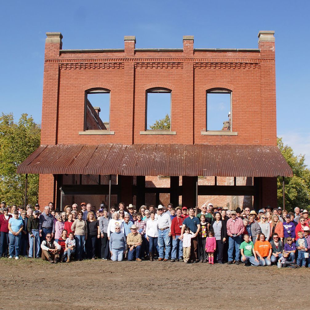 A large group of people pose in front of a brick building