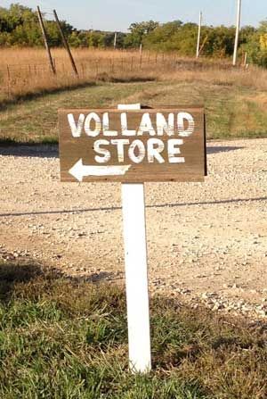 A wooden sign with an arrow pointing to the volland store