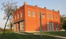 A large red brick building with a lot of windows and a tree in front of it.