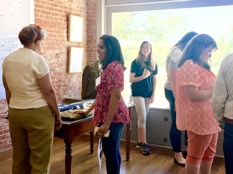 A group of women are standing in a room looking out a window.