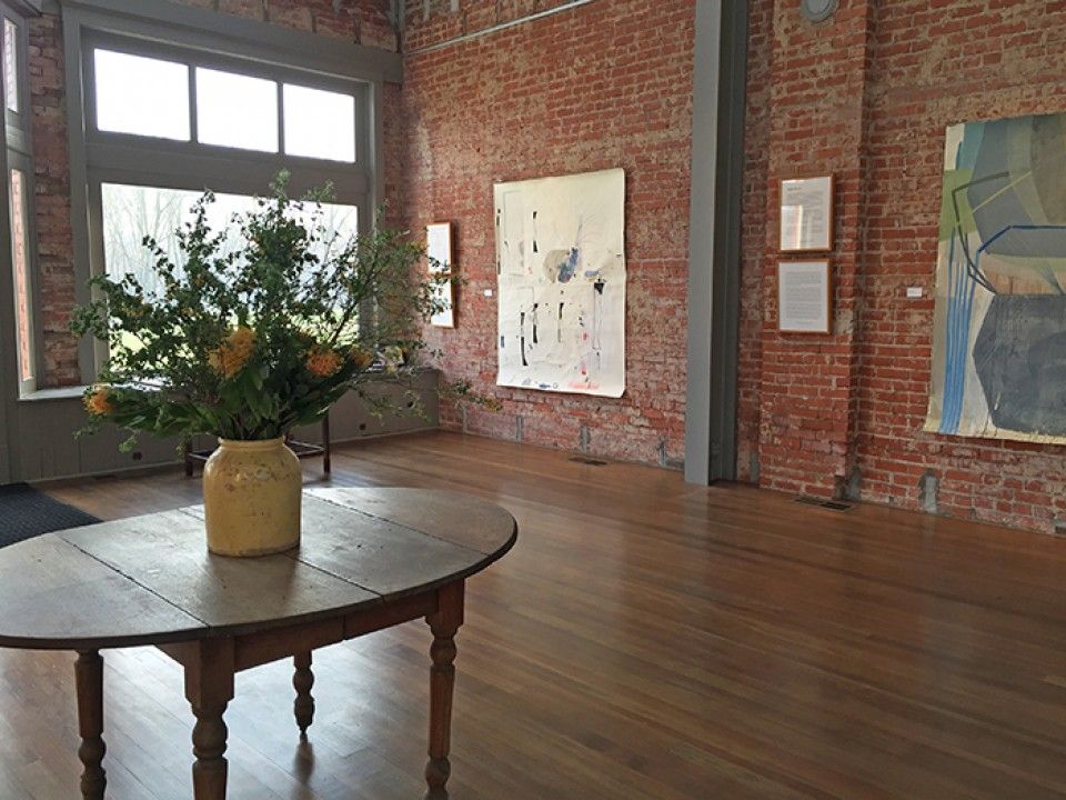 A table with a vase of flowers on it in a room with a brick wall.