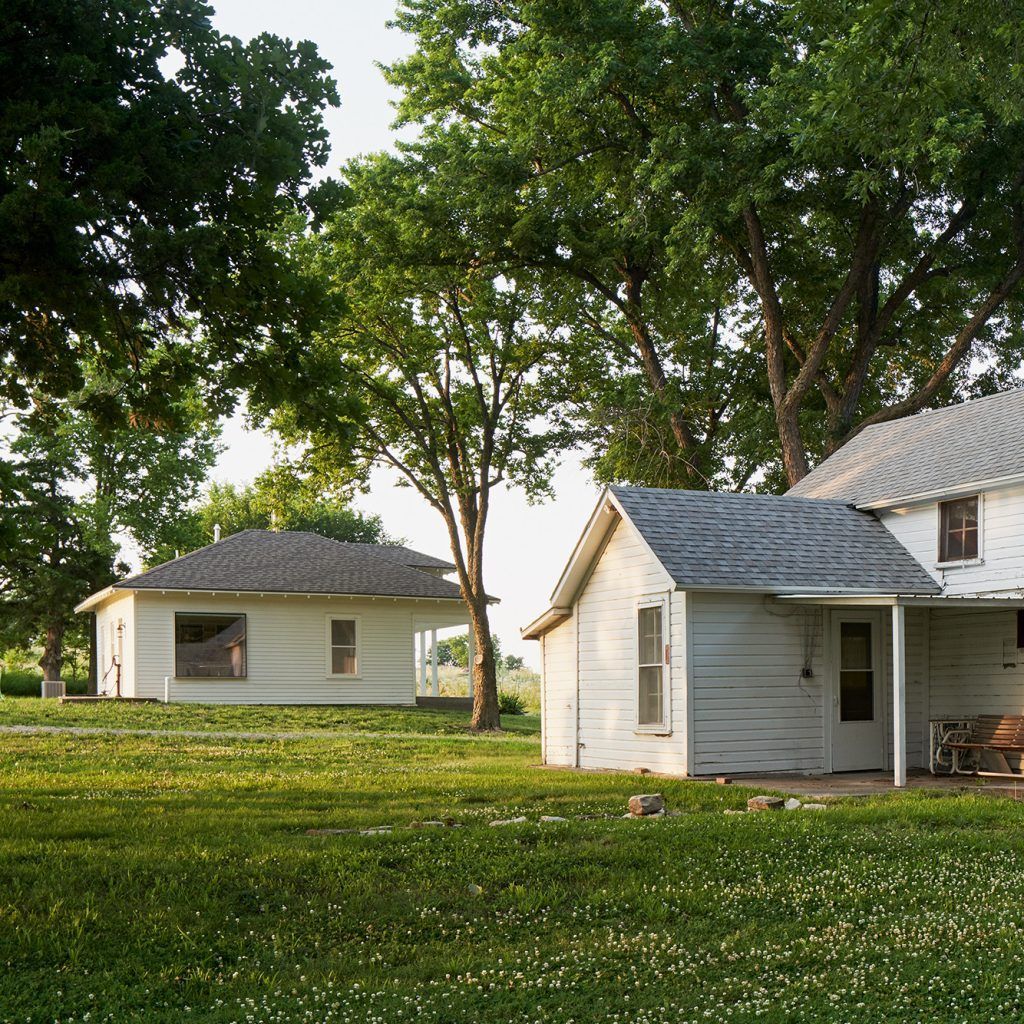 A white house with a gray roof sits next to a smaller white house