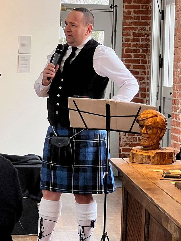 Bagpiper speaking at the microphone