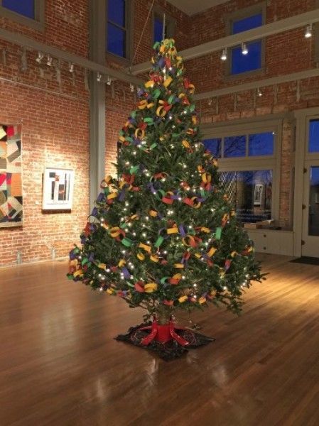 A large christmas tree in a room with a brick wall