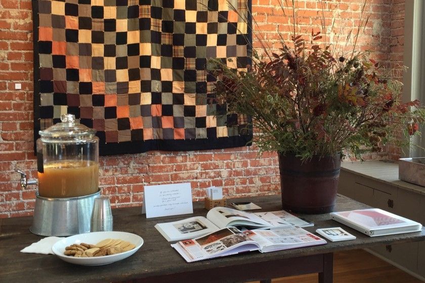 A table with a vase of flowers and a pitcher of juice on it.