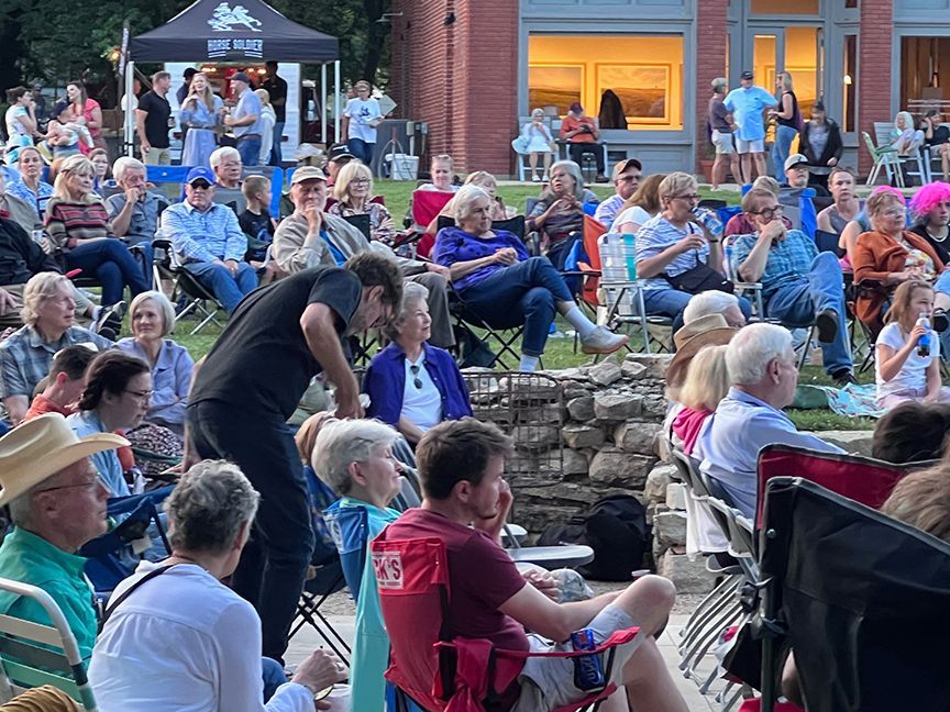 A large group of people are sitting in chairs watching a concert.