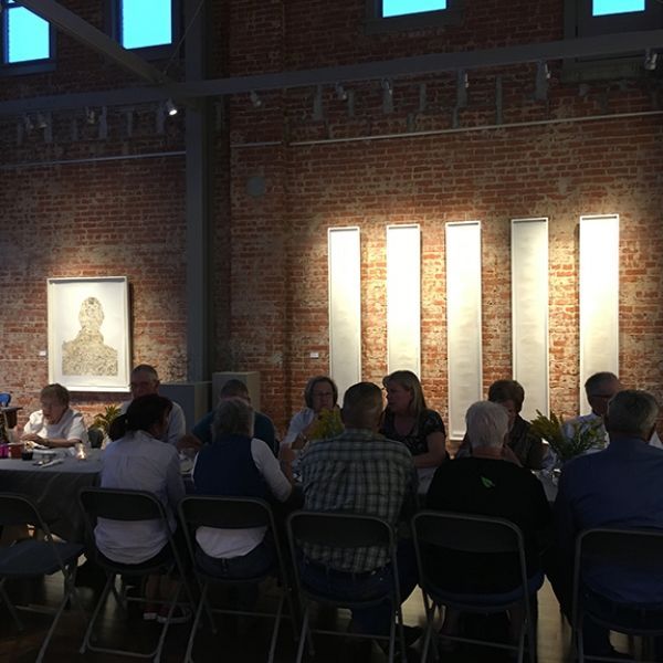 A group of people are sitting at tables in front of a brick wall