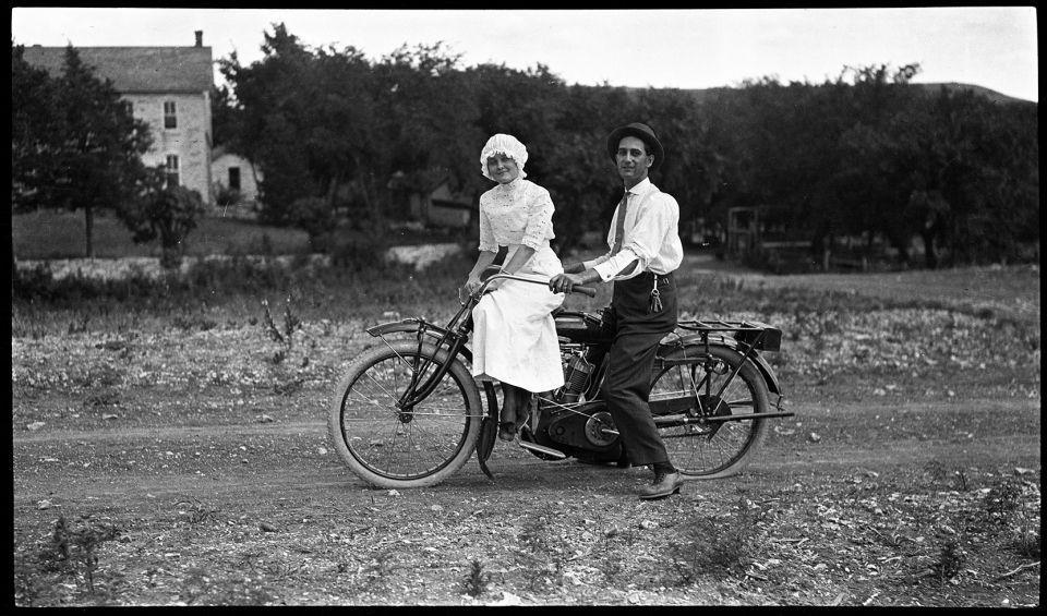 A man and a woman are riding a motorcycle on a dirt road.
