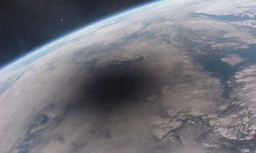 An aerial view of the earth from space with a black hole in the middle.