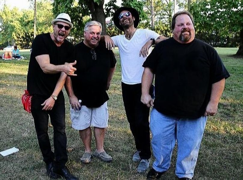 A group of men are posing for a picture in a park