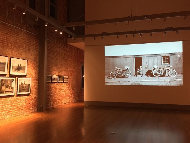 A large room with a projector screen displaying a black and white photo of motorcycles parked in front of a building.
