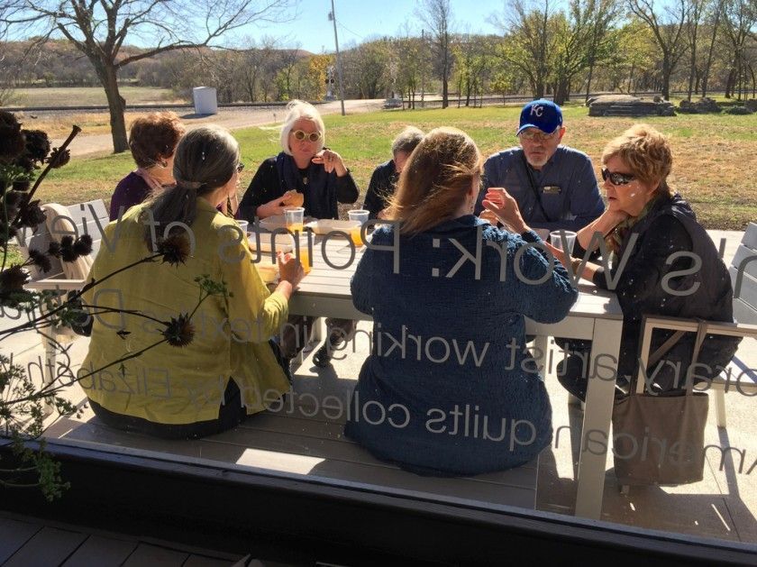 A group of people are sitting at a table outside eating food.