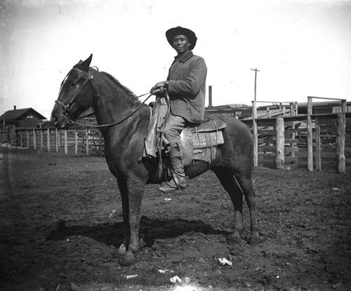 A black and white photo of a man riding a horse
