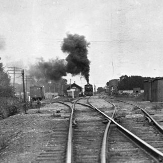 A black and white photo of a train going down train tracks.