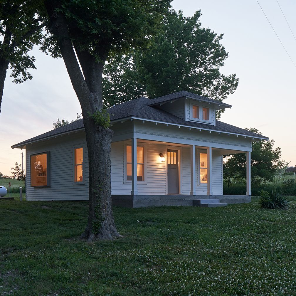 A small white house with a tree in front of it
