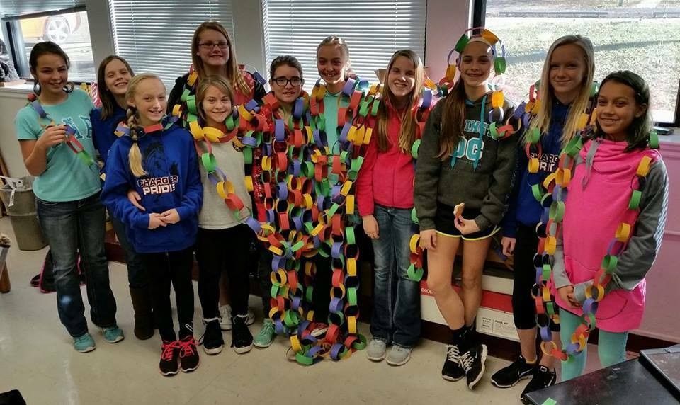 A group of young girls are posing for a picture in a classroom.