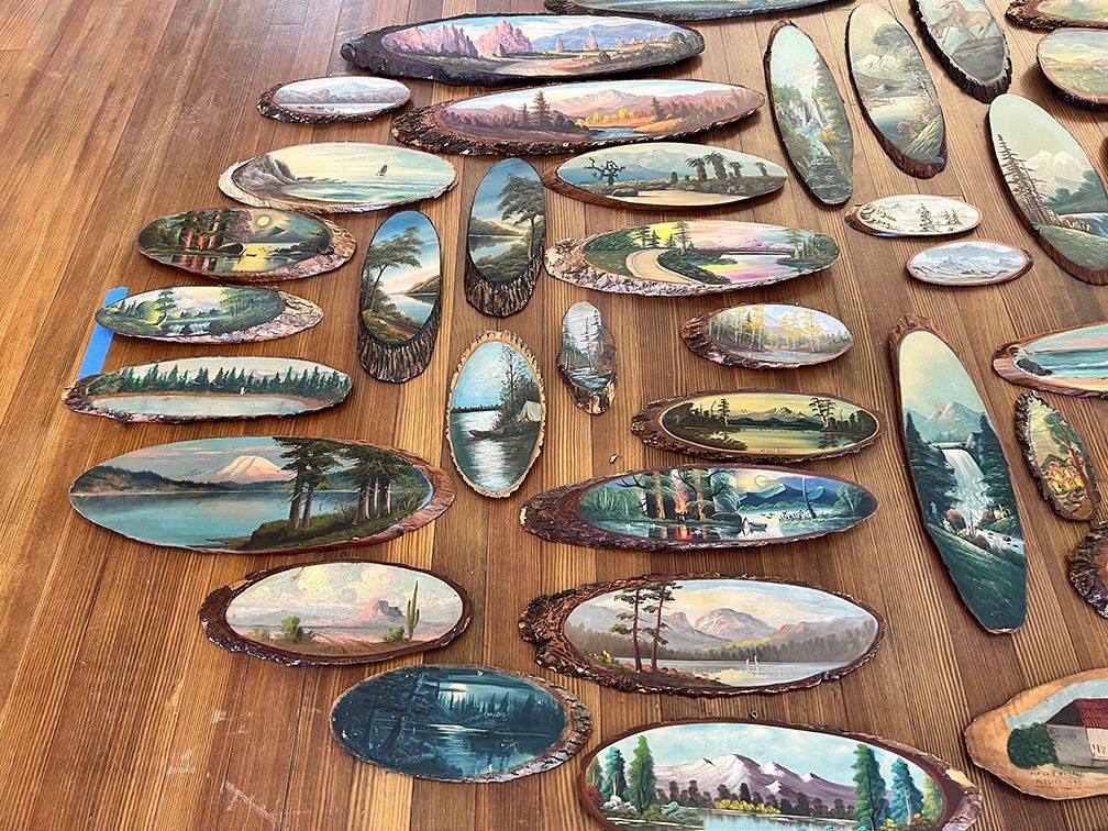 Log slab paintings arranged on the floor before installing the exhibit on the wall.