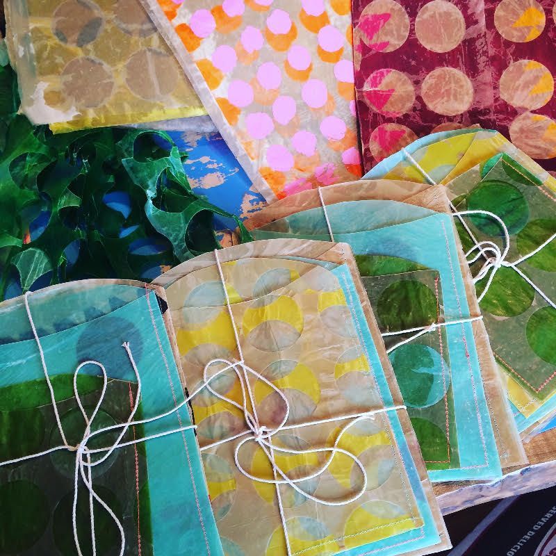 Bundles of colorful handmade paper tied with string. Various patterns and colors.