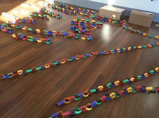 Colorful paper chains spread across a wooden floor, suggesting a classroom or craft project.