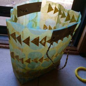 A yellow bag with triangles on it is sitting on a table next to a window.