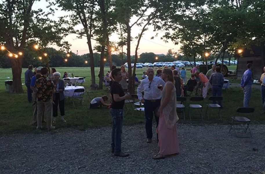A group of people are standing in a grassy area talking to each other