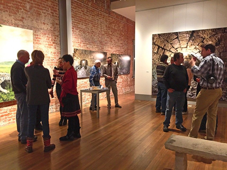 A group of people are standing in a room with paintings on the wall.