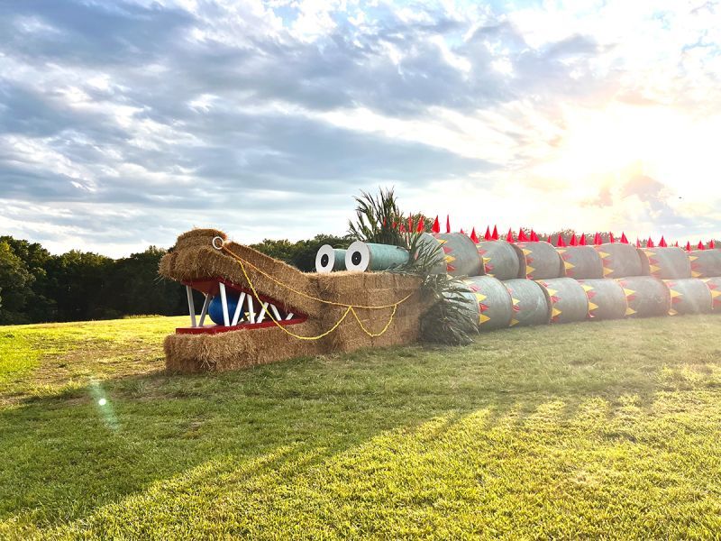 A crocodile made out of hay bales in a field.