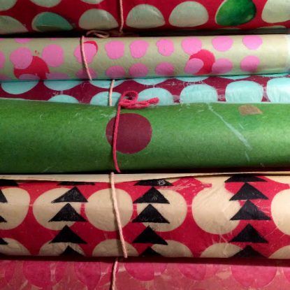 A bunch of rolls of wrapping paper are stacked on top of each other.