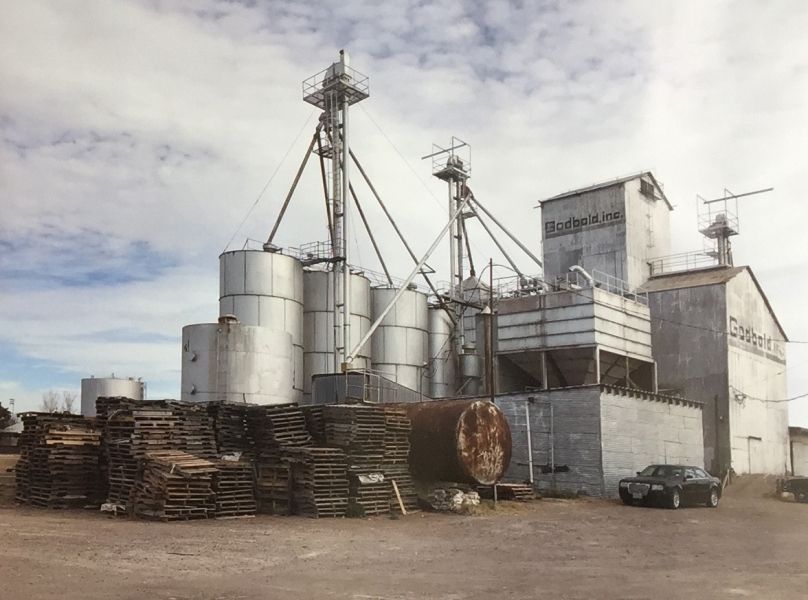 A car is parked in front of a large industrial building