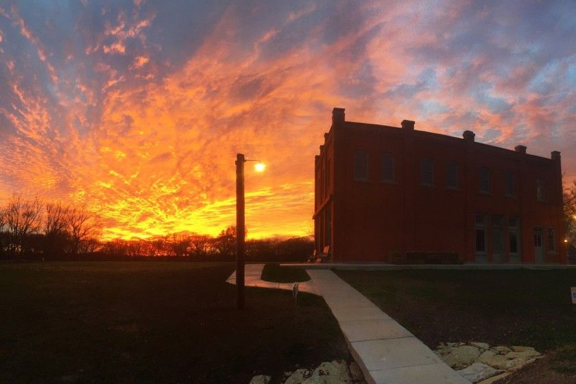 A large red building with a sunset in the background.