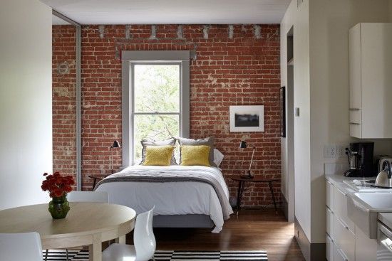 A bedroom with a brick wall and a bed