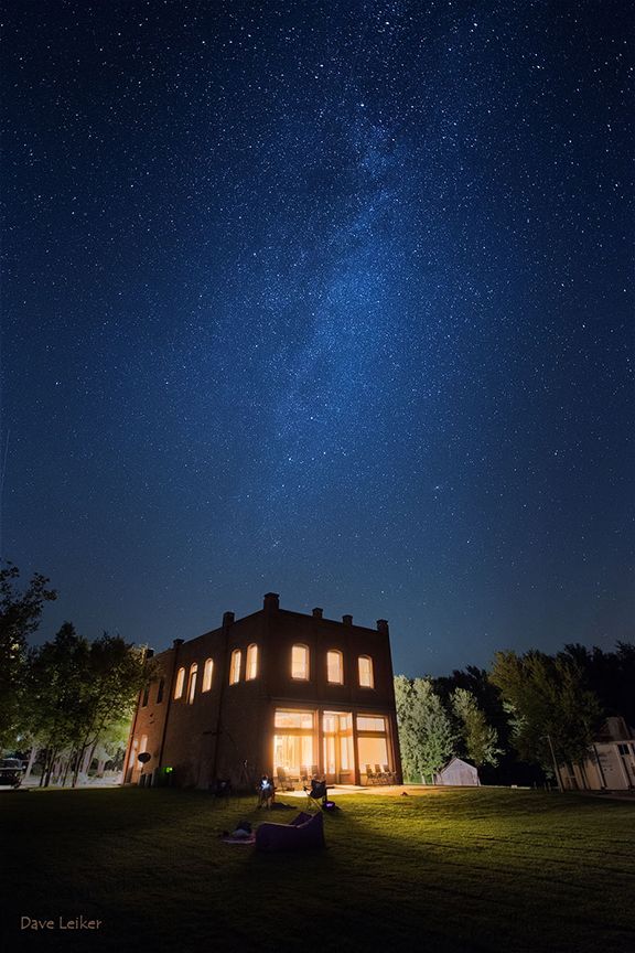 A house is lit up at night under a starry sky.