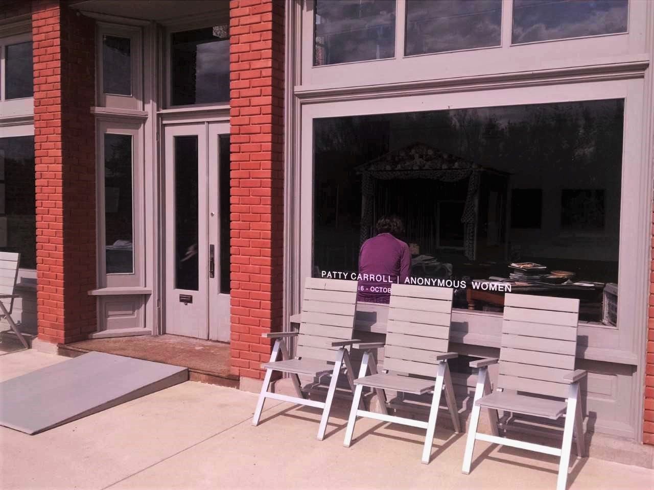 A man in a purple shirt sits at a table outside of a building