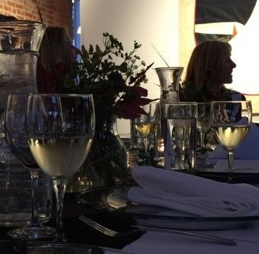 Wine glasses and setting on a table, silhouetted person in the background.