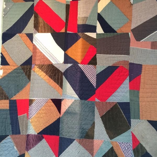 Abstract patchwork quilt with geometric shapes in various colors and textures.