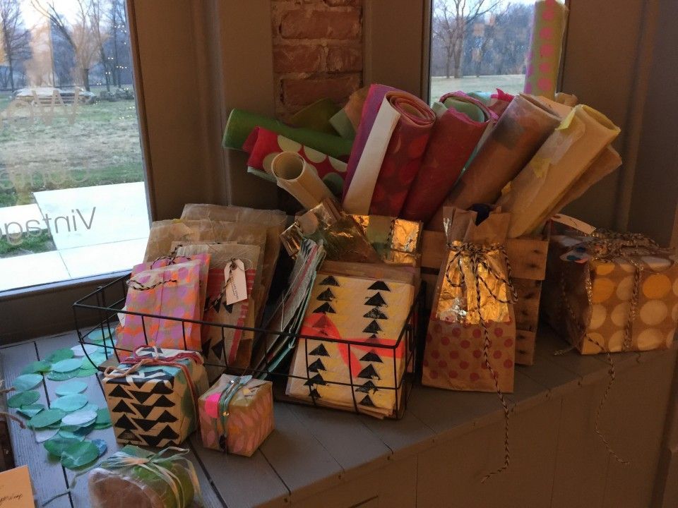 A bunch of wrapped gifts are sitting on a table in front of a window.