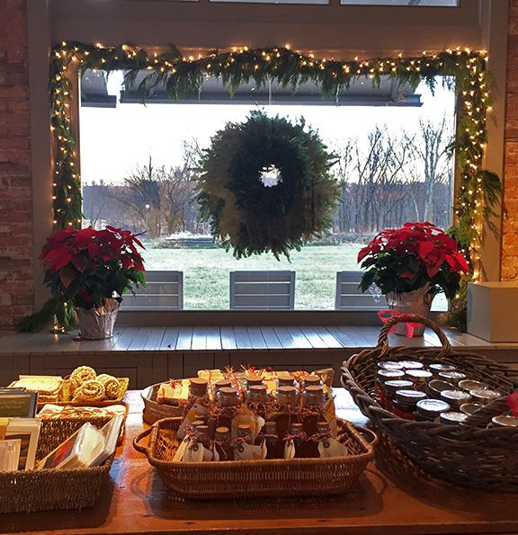 A festive display with food baskets, poinsettias, and a wreath in a window with outdoor view.